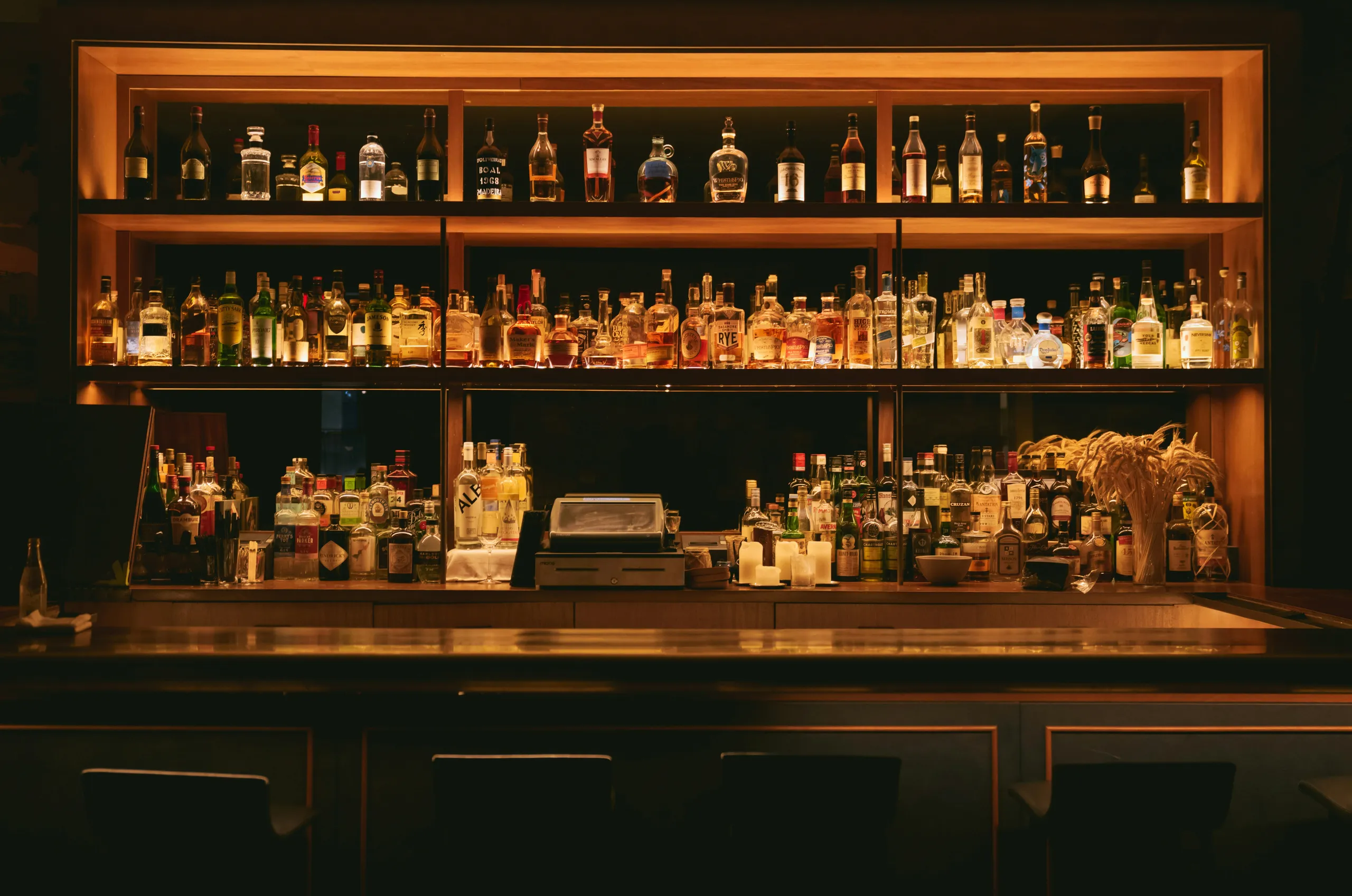 Bar con encanto con estantes iluminados llenos de botellas y una cálida luz nocturna.