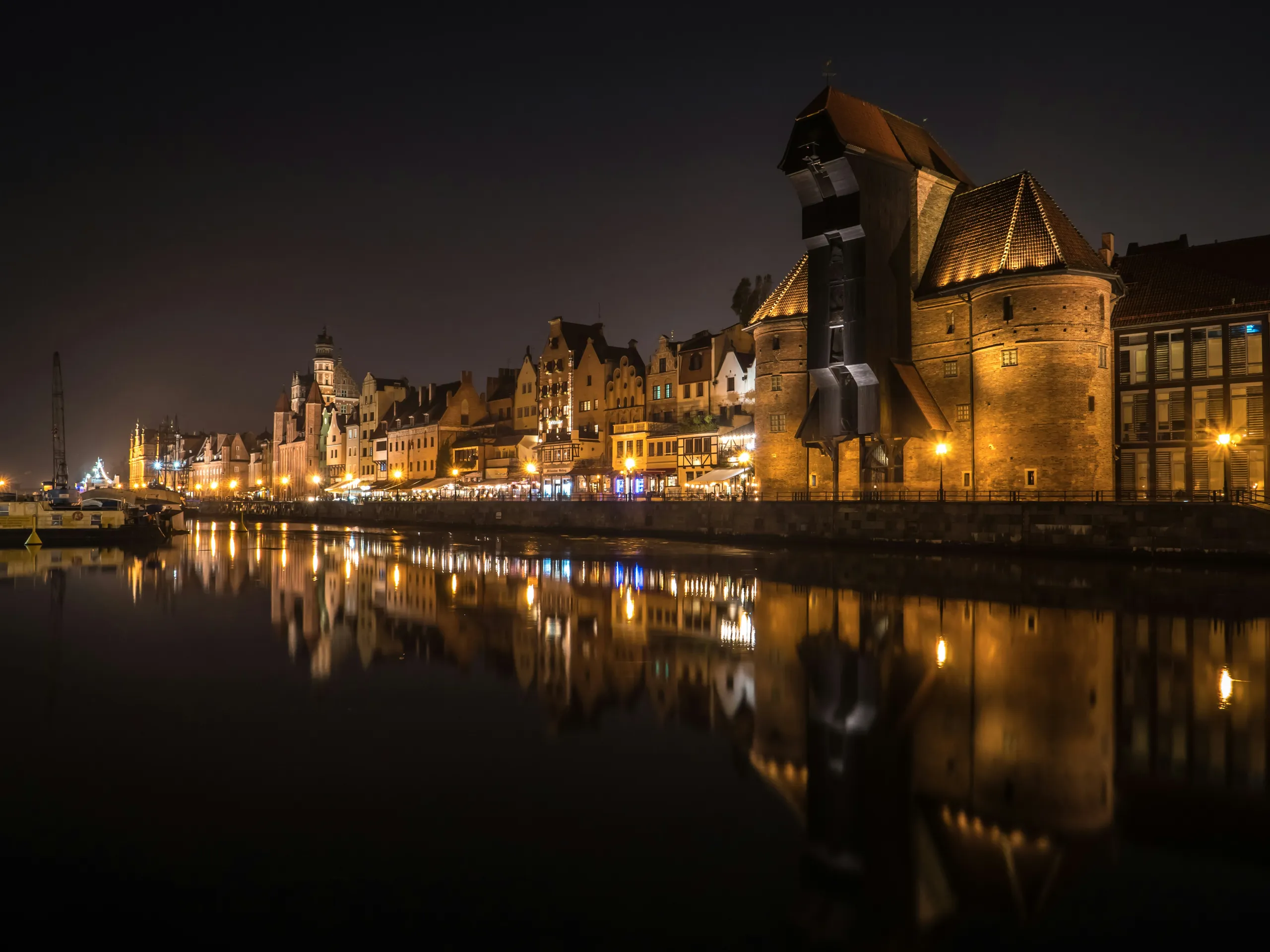 Panorama nocturno del muelle del Casco Antiguo: la Grúa iluminada, los edificios y los reflejos de las luces en el río.